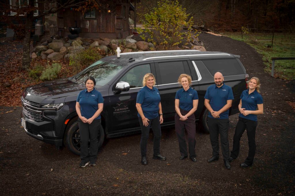 De ansatte i Færder Begravelsesbyrå står foran begravelsesbilen, klare til å hjelpe familier i Vestfold med verdig og personlig gravferd.